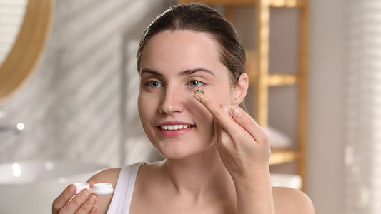 Girl looking at the mirror smiling and wearing a contact lens in her eye